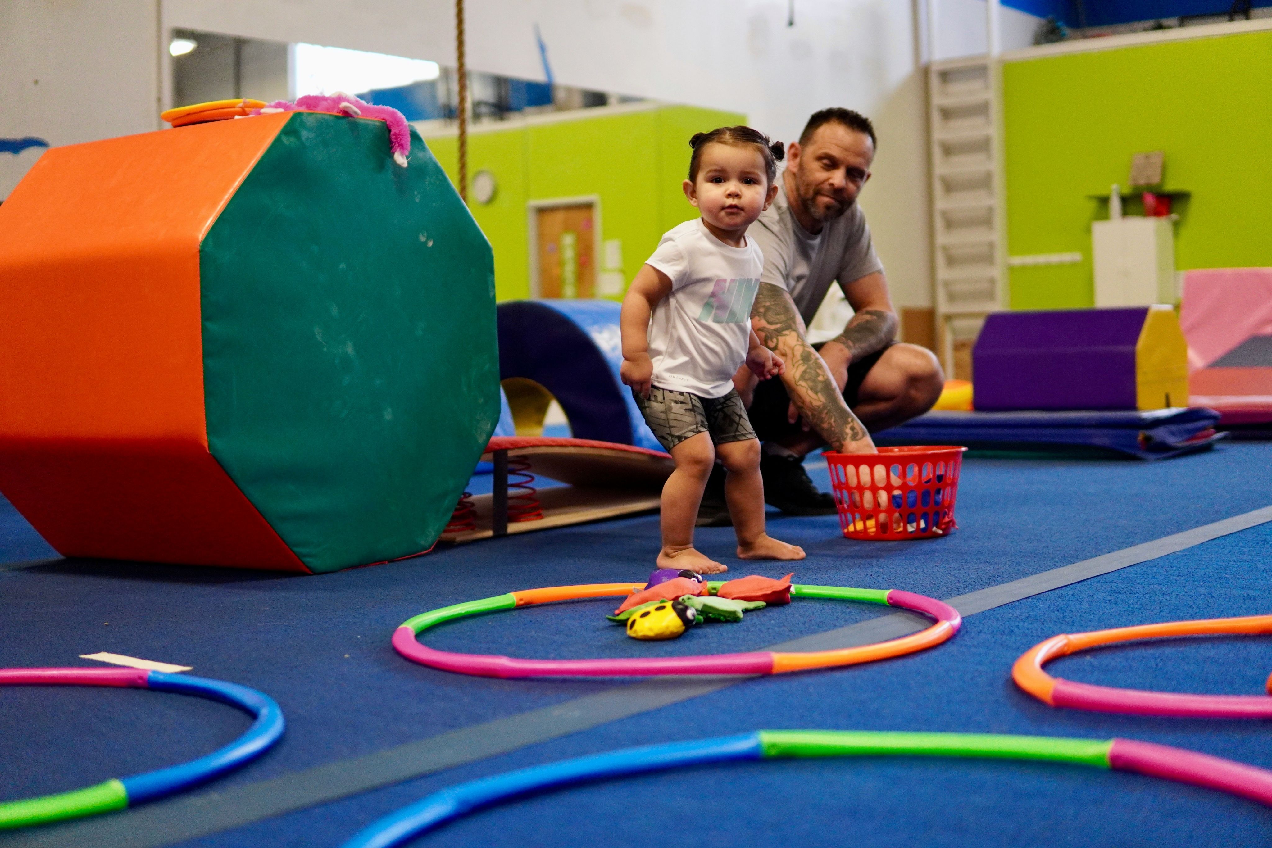 a person and a child playing with toys on a blue mat